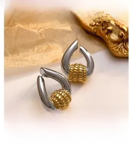 Close-up of two-tone U-shaped earrings with silver base and gold woven texture detail