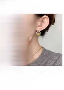Macro detail of mixed gold and silver teardrop earrings with textured weave design
