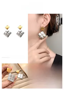 Detail view of bicolor geometric diamond earrings with rhombus pattern and gold accents