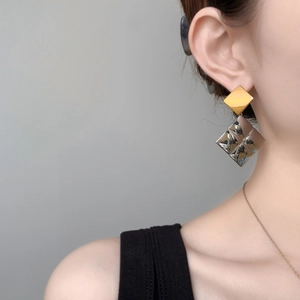 Geometric square tassel drop earrings in gold and silver finish on female model