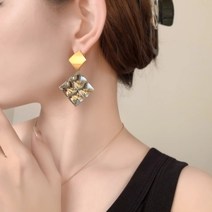 Detail of geometric square tassel earrings with radiant cut amber crystal on a model