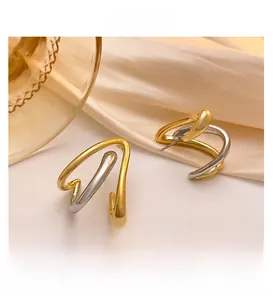 Detail view of geometric two-tone gold and silver C-shaped earrings on silk fabric