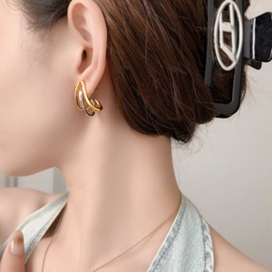 Detailed close-up of mixed gold and silver layered hoop earrings on a model's ear