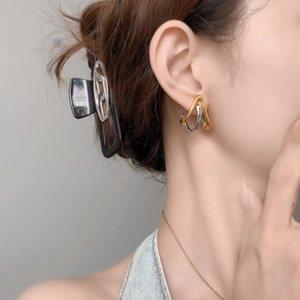 Detail of geometric two-tone gold and silver curved stud earrings on a model