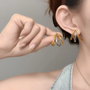 Detailed close-up of geometric two-tone gold and silver earrings on a model's ear