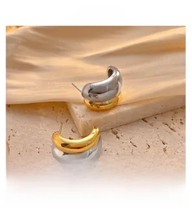 Detail of chunky C-shape earrings featuring contrast gold and silver metal finishes