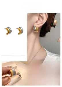 Macro shot of minimalist C-shape stud earrings with two-tone gold and silver plating