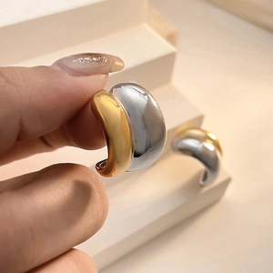 Macro shot of two-tone C-shape hoop earrings with polished gold and silver finish