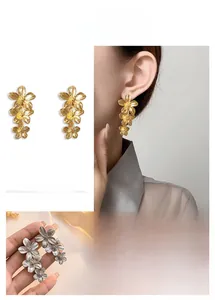 Vue détaillée des boucles d'oreilles fleurs étagées avec texture brossée en or et en argent