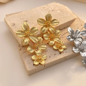 Détail des boucles d'oreilles fleur à plusieurs niveaux dorées et argentées texturées