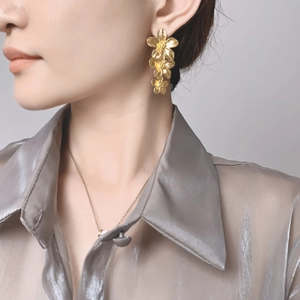Détail de boucles d'oreilles fleurs triple couche plaquées or 18 carats avec fini brossé