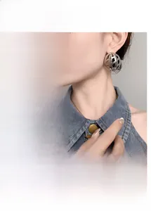 Detail of hollow geometric spherical stud earrings in gold and silver metallic finish