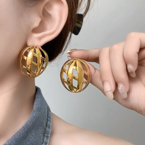 Macro detail of gold hollow spherical earring showing polished geometric hollow structure