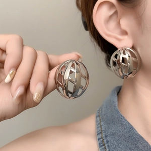 Macro view of large silver mesh hollow spherical stud earrings with polished metallic finish