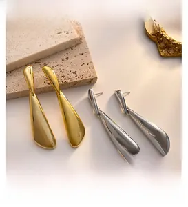 Detailed view of polished gold and silver irregular geometric drop earrings on stone