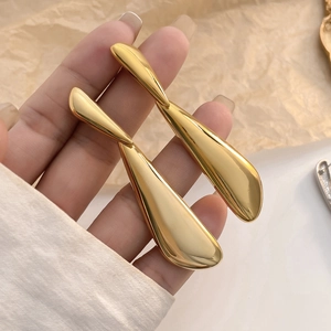 Elegant gold-plated droplet earrings with a polished metallic finish shown in a hand