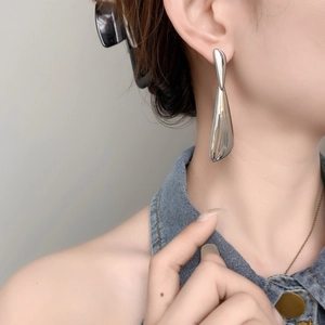 Close-up of geometric silver water drop earrings with a polished mirror finish on model