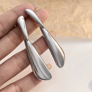 Macro shot of large polished silver teardrop earrings held to show texture and scale