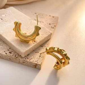 Detailed view of high-shine gold C-shaped earrings with unique gear-like texture