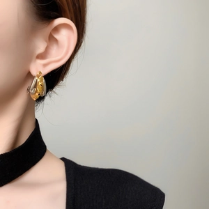 Macro detail of two-tone C-shaped geometric earrings in gold and silver finish