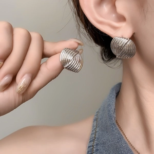 Nahaufnahme der fächerförmigen Silberohrringe mit Spiralmuster am Ohr des Models