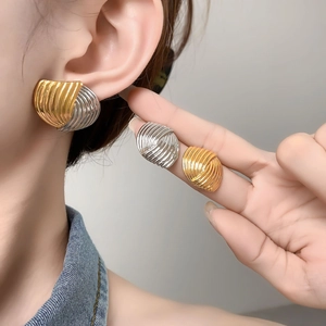 Detailaufnahme von fächerförmigen Ohrsteckern in Gold, Silber und zweifarbigem Design