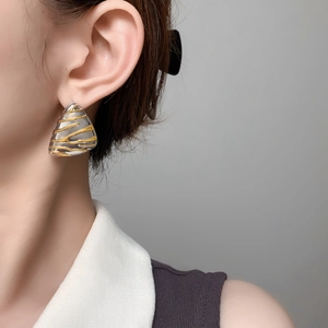 Macro detail of irregular triangle stud earrings with embossed gold wavy textures