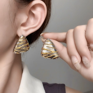 Close-up of irregular triangle studs with embossed lava texture on female ear