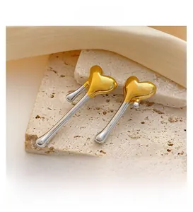 Close-up of heart-shaped gold and silver earrings on a stone display with silk