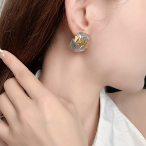 Boucles d'oreilles géométriques bicolores à texture rayonnante portées par un mannequin