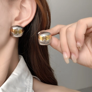 Détail de boucles d'oreilles carrées bicolores or et argent avec texture géométrique sur l'oreille
