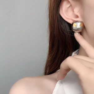 Gros plan de boucles d'oreilles sphériques bicolores avec motif en V gravé