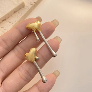 Detail of two-tone heart earrings with a unique fluid dripping design in gold and silver