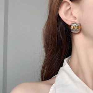 Détail de boucles d'oreilles bicolores or et argent avec texture tissée sur modèle