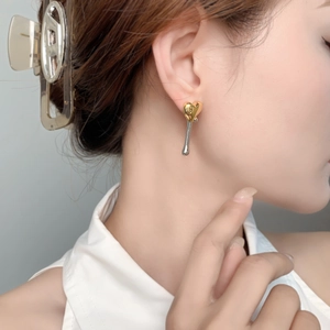 Detail of gold and silver heart earrings showing two-tone contrast on a female model