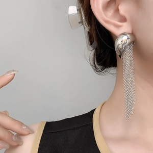 Close-up of elegant long silver tassel earrings worn, showing fluid chain movement