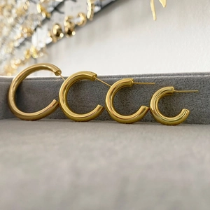 Set of four minimalist golden hollow hoop earrings in various sizes on grey velvet