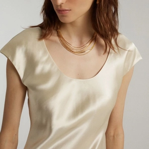 Detail of layered gold snake chain necklaces on model neck with satin dress