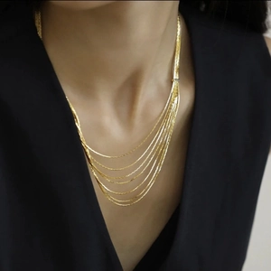 Close-up of multilayered golden snake chain necklace on model with elegant black dress