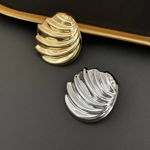 Polished shell-shaped wave earrings in gold and silver finish on a premium black background