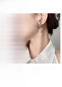 Detail of floral earrings with imitation pearl tassels and polished gold finish