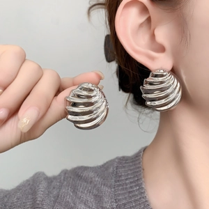 Detailed view of silver spiral wave earrings with textured polished metallic finish