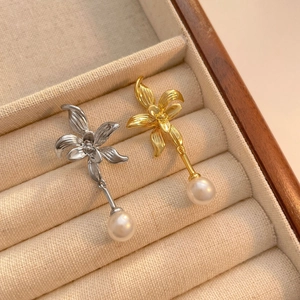 Detail view of gold and silver orchid flower earrings with elegant pearl tassels