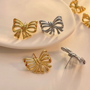Detailed close-up of bow knot stud earrings in polished gold and silver finishes