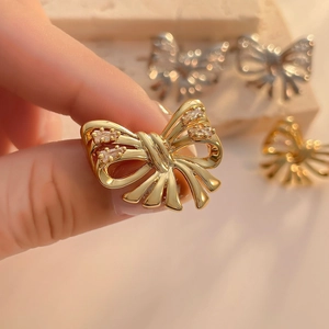 Detailed close-up of a gold bow-knot stud earring with sparkling cubic zirconia accents