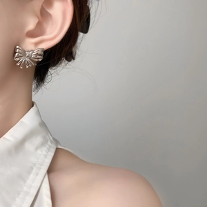Close-up of elegant silver bow stud earrings with polished metallic finish on a model