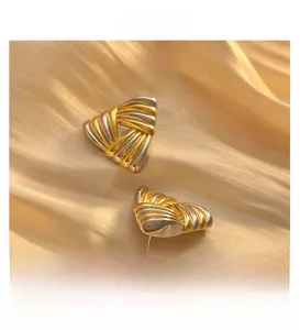 Nahaufnahme geometrischer Dreieck-Ohrringe mit gold-silberner gedrehter Metallstruktur