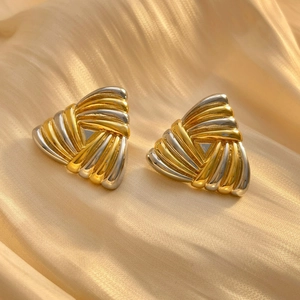 Makroaufnahme geometrischer Dreiecksohrringe mit zweifarbigen Gold-Silber-Wellenstrukturen