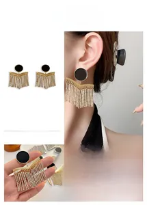 Detail of gold chain tassel earrings with black enamel inlay and zircon accents