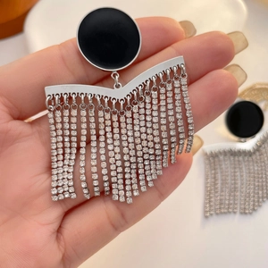 Detail of silver chain tassel earrings with black enamel disk and shimmering zircons
